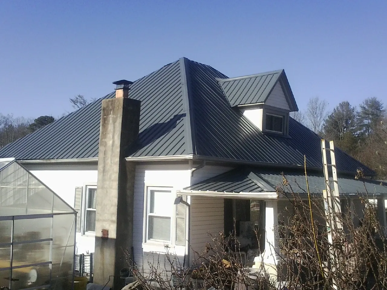 Dark blue standing seam metal roof on a white farmhouse with dormer — Slate & Tile Roof Repair by Roofing Brothers in Morris
