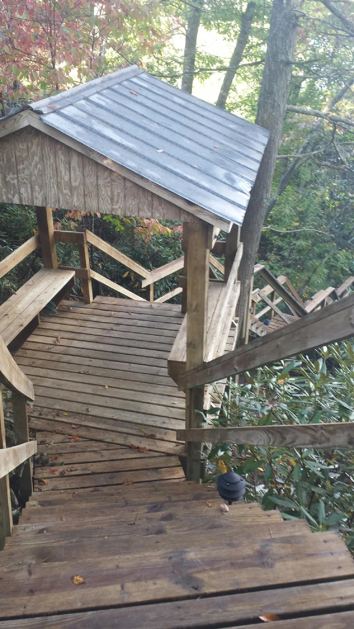 Metal roofed shelter over wooden steps on a wooded walkway — Skylight Repair & Installation work by our crew in Morris